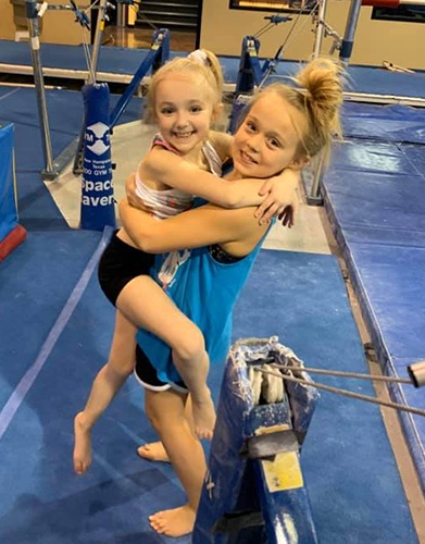 Two girls hugging and smiling in the gym
